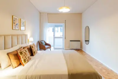 a bedroom with a large bed and a chair at 3BR Joyous Wonder by LovelyStay in Porto