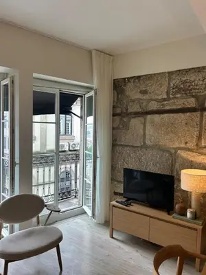 a living room with a tv and a stone wall at Largo São Domingos by Innapartments in Porto
