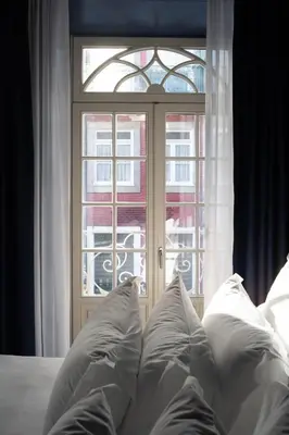 a bed with white pillows in front of a window at Hotel Kodawari Flores - by Kodawari Residences in Porto