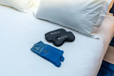 a bed with a pair of gloves and a blue ticket at Hotel Kodawari Flores - by Kodawari Residences in Porto