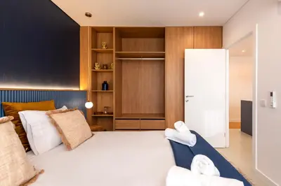 a bedroom with a large white bed and wooden cabinets at DoisPontoZero NAVY in Porto