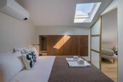 a bedroom with a large bed with a skylight at Portobliss Apartment in Porto