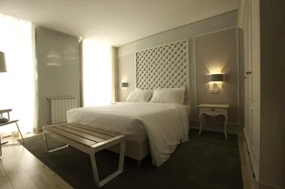 a bedroom with a large white bed and a bench at In Porto Gallery Guesthouse in Porto