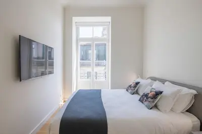 a white bedroom with a bed with pillows on it at Aliados Living Apartment in Porto
