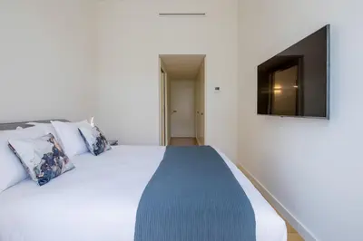 a bedroom with a white bed with a television on the wall at Aliados Living Apartment in Porto
