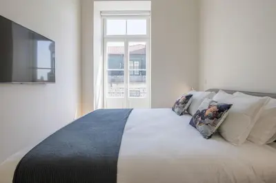 a bedroom with a white bed with pillows and a window at Aliados Living Apartment in Porto