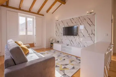 a living room with a couch and a stone wall at Almada Prime Apartment II in Porto