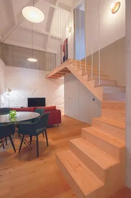 a staircase in a living room with a table and chairs at Andrade Rooftop Duplex in Porto