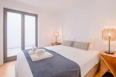 a bedroom with a white bed with towels on it at Canto Flores in Porto