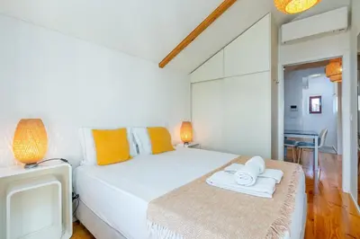 a white bedroom with a bed and a tv at Catedral da Sé Apartment in Porto