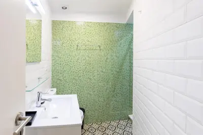 a bathroom with a sink and a green tiled shower at Trindade Trendy Studio 15 in Porto