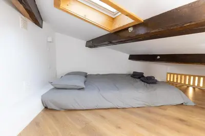 a bed in a room with white walls and wooden floors at Trindade Trendy Studio 17 in Porto