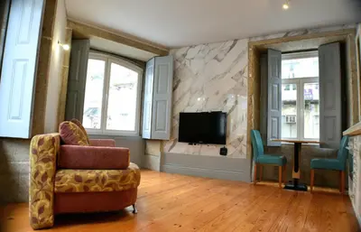 a living room with a tv and two chairs at Ribeira Riverview Panoramic in Porto