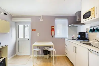 a kitchen with white cabinets and a table and stools at Island House in Porto