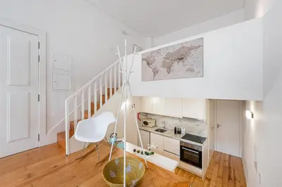 a white kitchen with a staircase and a white chair at GuestReady - A lovely city retreat in Porto