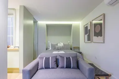 a bedroom with a bed and a purple couch at Pleasant Studio Santa Catarina in Porto