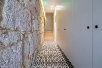 a hallway with a stone wall and a tile floor at Pleasant Studio Santa Catarina in Porto