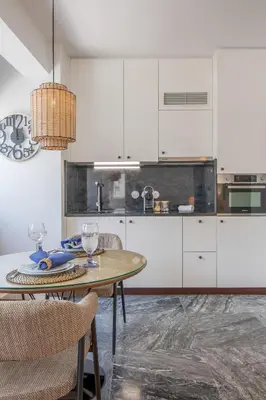 a kitchen with white cabinets and a table and chairs at PS70 Apartments I in Porto