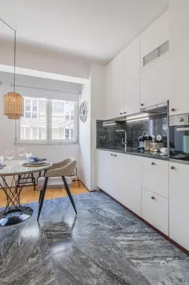 a kitchen with white cabinets and a table in a room at PS70 Apartments I in Porto