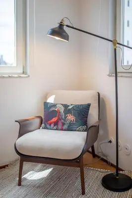 a lamp sitting next to a chair with a pillow at PS70 Apartments I in Porto