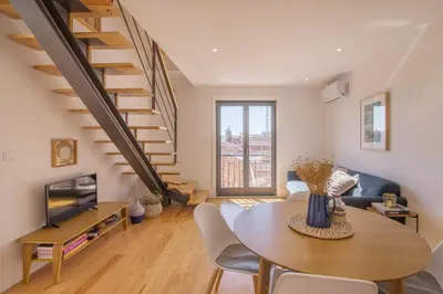 a living room with a table and a staircase at Topo Flores Apartment in Porto