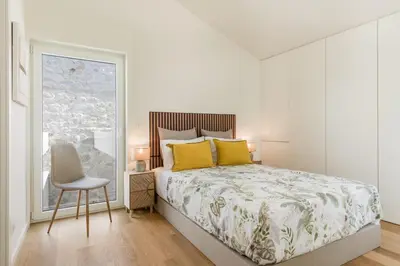 a bedroom with a bed and a chair and a window at Valadouro Duplex Factory - Maison dans Porto in Porto