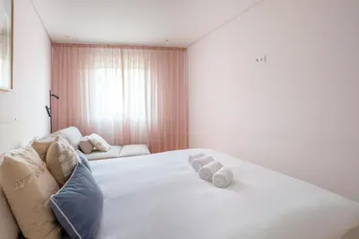 a bedroom with a large white bed with towels on it at Modern Camões Flat, In the Heart of Porto in Porto