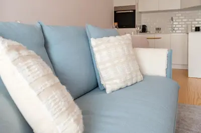 a blue couch with two white pillows on it at Modern Camões Flat, In the Heart of Porto in Porto