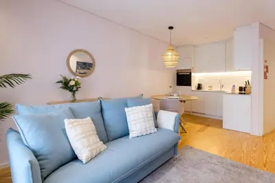 a living room with a blue couch and a kitchen at Modern Camões Flat, In the Heart of Porto in Porto