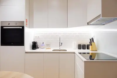 a white kitchen with white cabinets and a sink at Modern Camões Flat, In the Heart of Porto in Porto