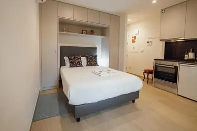 a bedroom with a large white bed and a kitchen at Carmo Residence Porto by Vacationy in Porto