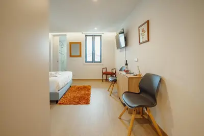 a bedroom with a bed and a desk and a chair at Carmo Residence Porto by Vacationy in Porto