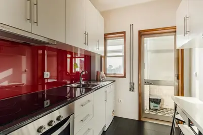 a kitchen with white cabinets and red walls at GuestReady - Bonfim Cozy Retreat in Porto
