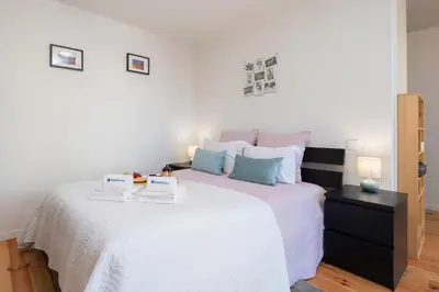 a bedroom with a large bed with white sheets and blue pillows at Stylish Studio in Porto Downtown by HostWise in Porto