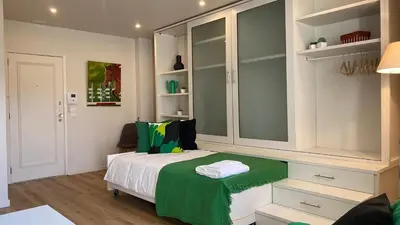 a bedroom with a bed with a green blanket on it at BEST - Studio Trindade with AC and Parking in Porto