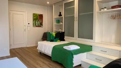 a bedroom with a bed with a green blanket on it at BEST - Studio Trindade with AC and Parking in Porto