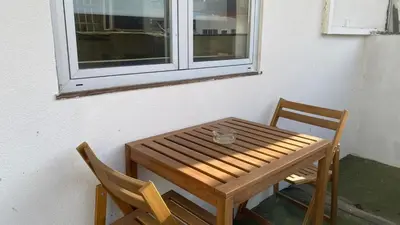 a wooden table and two chairs in front of a window at BEST - Studio Trindade with AC and Parking in Porto
