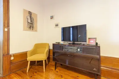a living room with a television and a chair at Downtown Classic Apartment in Porto