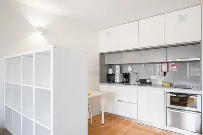 a white kitchen with white cabinets and appliances at GuestReady - Mandariam Studio in Porto
