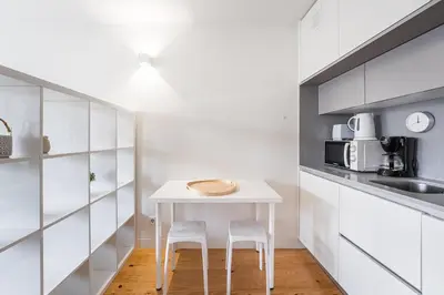 a small white kitchen with a table and two stools at GuestReady - Mandariam Studio in Porto