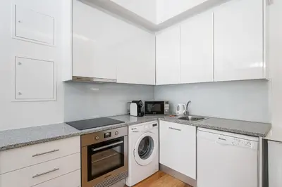 a kitchen with white cabinets and a washer and dryer at GuestReady - Boutique style loft in Constitution in Porto