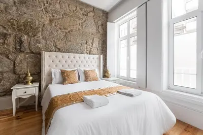 a bedroom with a large white bed with a stone wall at GuestReady - Boutique style loft in Constitution in Porto