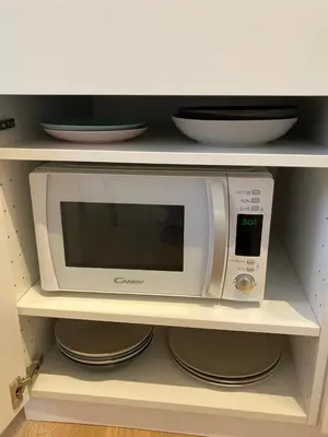 a microwave in a kitchen shelf with plates and bowls at Trindade Studio by Portomosa in Porto
