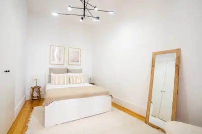 a white bedroom with a bed and a mirror at Chic 1BR in República w Balcony by LovelyStay in Porto