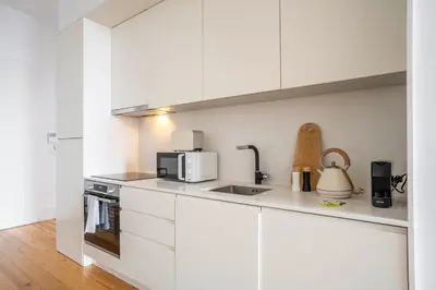 a white kitchen with a sink and a microwave at Chic 1BR in República w Balcony by LovelyStay in Porto