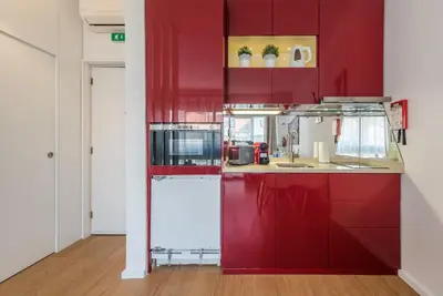 a kitchen with red cabinets and a microwave at GuestReady - Fabric in Colors in Porto