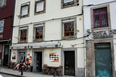 a building on a street with two people sitting outside at T2 suites com vistas rio Douro in Vila Nova de Gaia