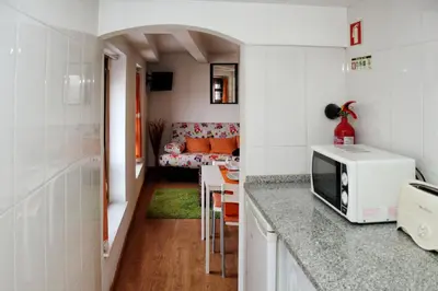 a kitchen with a microwave and a living room at Estúdio com vistas rio Douro in Vila Nova de Gaia