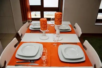 a table with white plates and glasses and orange table cloth at Estúdio com vistas rio Douro in Vila Nova de Gaia