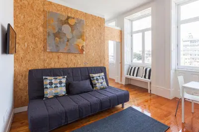 a living room with a blue couch and two windows at BO - Sá da Bandeira in Porto